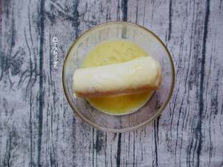 6、香蕉土司卷,将卷好的香蕉卷放入蛋液中,均匀的裹上蛋液