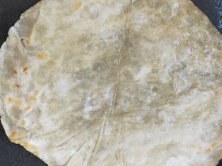 3、街头手抓饼的吃法----懒人必备早餐,放入手抓饼生胚，煎至一面定型后翻个面在煎至另一面，直到煎至两面稍微油金黄色 