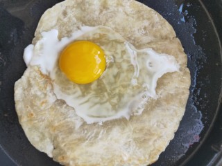 4、街头手抓饼的吃法----懒人必备早餐,打入一个鸡蛋在手抓饼饼上，关掉电饼铛下档，盖上盖子焖30秒。