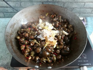 11、紫苏炒田螺,田螺翻炒几分钟,加入酱油,蒜片和姜丝,冰糖继续大火翻炒,