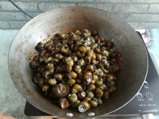 10、紫苏炒田螺,加入田螺大火翻炒,一定要用深的铁锅,如果用不粘锅容易刮花涂层,用深的铁锅也比较方便翻炒