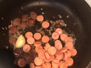9、黄金腊肠火腿蛋炒饭,在加点橄榄油，然后就把腊肠火腿和菜圃放入，改小火慢煎。煎熟后盛起来放一旁备用。