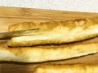 2、私家版培根牙签油条,用剪刀从中间把里面一层白色的部分如图剪开。