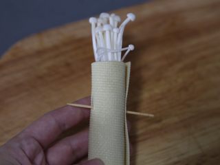 7、豆皮金针菇卷,从一边卷起，再用牙签固定好