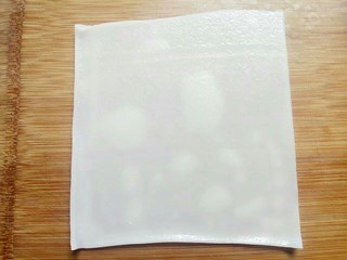 9、河粉包肉之卷河粉,取一张河粉皮在占板上面