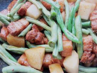 6、五花肉豆角焖面,倒入土豆跟豆角大火翻炒,翻炒至豆角变色,翻炒一分钟左右就可以