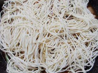 8、五花肉豆角焖面,水减少一半时,在最上面平铺面条,铺的均匀一点,盖上锅盖闷10-15分钟