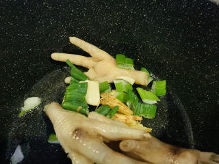 8、明虾鸡爪煲,锅里再加1勺油，鸡爪放入锅里，炒香，加蒜瓣大葱叶和姜片；