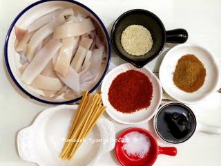 1、烤鱿鱼,把所有需要用到的材料都先准备好，先把鱿鱼洗干净，撕去红皮，鱿鱼须的吸盘用剪刀剪掉，把鱿鱼切成条