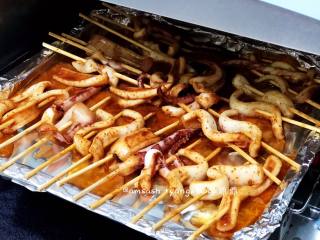 7、烤鱿鱼,中途戴上防热手套，把烤盘拿出，把烤盘中的汤汁倒掉