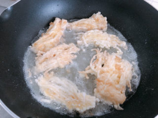 10、油炸金针菇,放入锅内油炸。