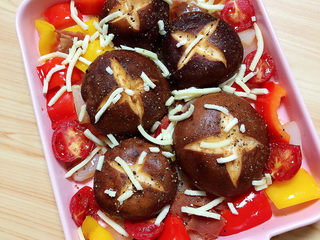 16、孜然烤香菇,零散的加一些芝士碎。将烤盘放入烤箱中，180度烤15分钟。