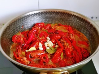 9、爆炒小龙虾,加入切好的姜蒜，盖上盖子烧开后转中小火15分钟左右。