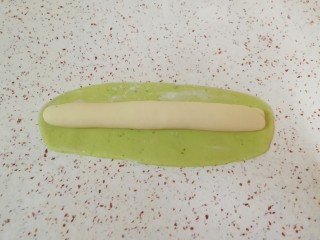 12、猪肉白菜水饺,白色的长条状面团放在绿色的长方形面团上,卷起来。
