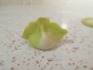 16、猪肉白菜水饺,把饺子边缘捏上,然后用两个手的食指和大拇指一起挤捏一下,一个白菜饺子就包好了,有没有很像白菜呢?