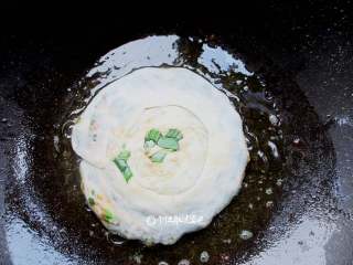 11、家常韭菜饼,平底锅涂一层油,油温热后转小火放入韭菜饼坯子,煎一会就翻转过来煎另一面,煎的过程要两面不断翻转避免煎焦。煎到两面金黄即可。由于面团是卷的,建议多煎一会让卷在里面的面也熟透。