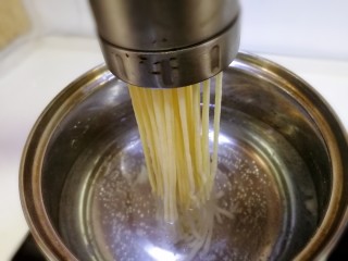 14、酸菜肉丝面,饧好的面团更柔软，分两块儿放入压面机里，水开压出面条。