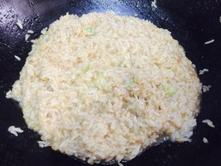 5、鸡翅焖饭,鸡翅盛盘，剩米饭与大葱倒入锅里，合着汤汁炒一下。