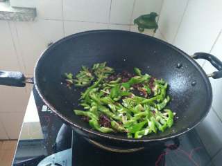 6、干煸香菇,放入蒜片和青椒丝炒香；