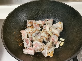 5、四季豆烧排骨,烧热锅下油，放蒜爆香，下排骨，煎两面金黄色。