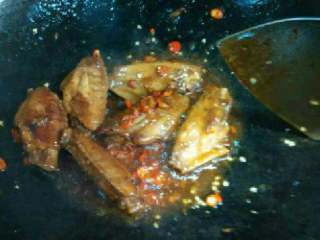 5、红烧鸡翅,盖上锅盖，大火煮滚转小火煮5～8分钟，千万别糊了， 还剩下许多汤汁，大火收汁， 放少许耗油。 放辣椒，大蒜末加少许盐 拌匀，因为事先腌渍过所以盐放一点点就可以了