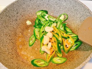 5、辣炒鸡肉,锅里再倒入适量油，把青椒和大蒜炒香，炒至辣椒表皮微微焦黄