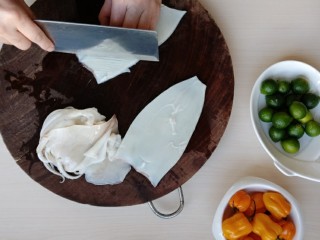 2、鲜辣酸柑鱿鱼,取一块鱿鱼片，肉面朝上，从一个角开始，横着直刀轻轻切若干平行的条纹，深度为鱿鱼的3/4，注意不要切到底，别切断了。