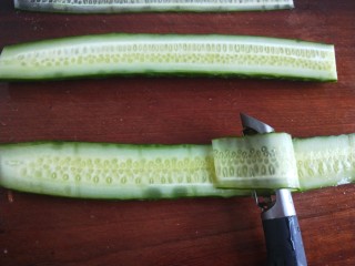 5、凉拌黄瓜卷,用刮皮刀来刮成长片。