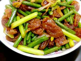 5、蒜苔炒腊肠,接着放入蒜苔，加盐，生抽炒至断生后加鸡精即可