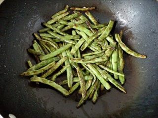 2、干煸豆角,3．	锅中倒入适量的油，油热后将豆角放入锅中，中火开始煸炒。煸炒至豆角表面起皱收缩，呈微黄色时即可捞出。煸好的豆角迅速浸入冰水中