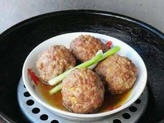 6、四喜丸子的做法,取四个“四喜丸子”放入盘中,加葱段、生抽、少许盐、味精、水。放入蒸锅。