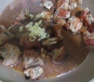 6、豉椒炒排骨,加入姜末和蒜蓉再炒片刻，加入酱油，糖和没过排骨的清水，盖上盖子，中小火让排骨充分吸收调味料