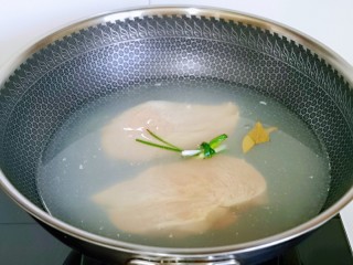 4、手撕鸡胸肉,锅中加水，料酒，葱，姜片烧开，放入鸡胸肉大火煮4-5分钟，焖3分钟。