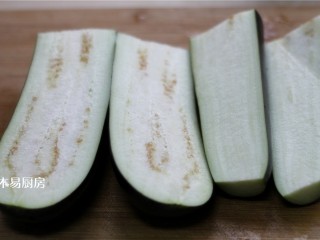 3、蒜泥手撕茄子,长茄子切去蒂，从中间剖开，切断。这样做是为了让茄子在很短的时间蒸熟。