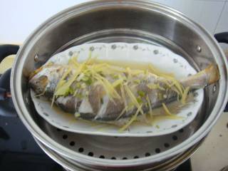 8、清蒸黄鱼,水开后加入大火蒸10分钟之后打开把鱼上的姜丝和葱花去掉，把盆内水倒掉