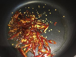 10、四川+酒鬼花生,倒出锅内多余的菜籽油，留一点点，倒入切丝的红辣椒和一小碟花椒粒，炒香