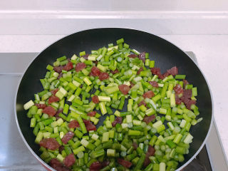 4、蒜苔炒腊肠,然后倒入蒜苔一起翻炒。其间要撒点开水防焦