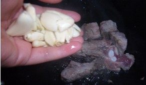 2、干炒橙香排骨,将大蒜拍烂放入排骨中继续煸炒