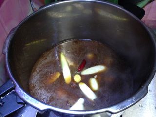 9、酱烧牛蹄筋,倒入高压锅，下入葱、姜、花椒、大料、辣椒，调入料酒、糖（如果觉得颜色浅，可以加入适量老抽）