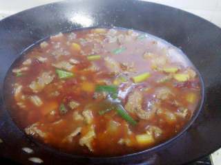 7、水煮牛肉,迅速一片片放入牛肉滑开,大火烧开后煮至牛肉变色,加入大葱叶段,调入盐味鸡精即可关火。