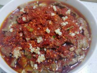 8、水煮牛肉,倒入装了菜的汤碗中。将花椒粉,辣椒粉和剩余蒜末均匀洒在肉片表面。