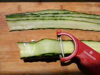 3、凉拌黄瓜卷,选一个直一些的黄瓜洗干净，去掉两端，用刮皮器刮成片状