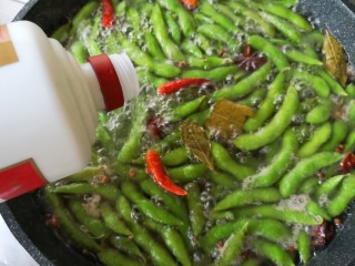 8、香辣毛豆,煮5分钟后,倒一点白酒下去,白酒一定要放,成品滋味会香很多。