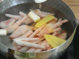 2、柠檬百香果凤爪—看世界杯的下酒菜,冷水入锅，放入葱段、姜片，加入料酒。