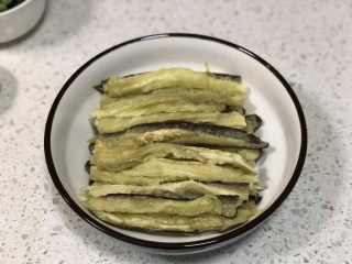 7、凉拌手撕茄子,取出蒸熟的茄子，放温热不烫手后先把每一半茄子对半切开，然后用手撕成小长条，摆放在盘子内