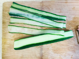 4、蒜泥黄瓜,左手按住黄瓜，右手用刮刀从左边刮向右边，刮成一条条的薄片