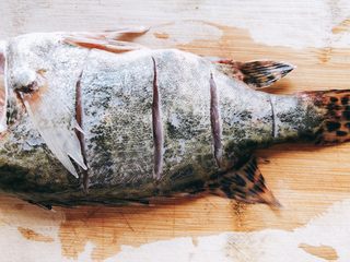 2、年年有余之糖醋鱼-年夜饭,先在鱼身上竖刀切4刀,切至鱼骨位置停止,不切断鱼骨。