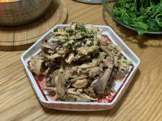 11、盐焗手撕鸡,稍凉一点的时候，顺着鸡架撕成小块，放入锅底的鸡汁，撒上葱花和炒香的白芝麻拌匀