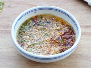 7、绿豆凉粉,大蒜和姜切碎,香葱切葱花。将葱姜蒜连同辣椒面和芝麻放入小碗中,锅中倒适量食用油烧热后浇倒在碗中的食材上,榨出香味。