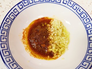 13、自制猪皮冻,将热油浇在姜蒜末和辣椒粉上。 